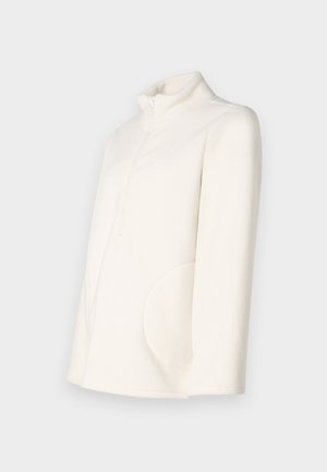Giacca in pile color avorio con maniche lunghe, colletto alto, zip frontale a metà e tasche laterali arrotondate su uno sfondo semplice.