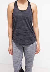 Zwart en grijs gestreept sporttanktop met een afgeronde zoom, gecombineerd met grijze leggings met horizontale strepen en zwarte accenten.