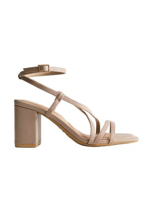 Sandale beige à talon haut bloc, avec fines lanières croisées sur les orteils et bride réglable à la cheville avec boucle.