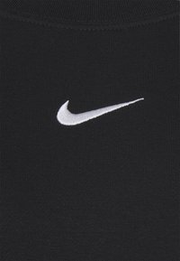 Černá bavlněná mikina s bílým vyšitým logem Nike ve tvaru „swoosh“ na hrudi. Materiál má měkký, texturovaný vzhled.