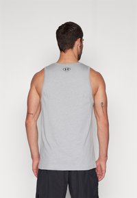 Débardeur de sport gris avec un col arrondi et un logo au niveau du haut du dos ; doté d'un tissu léger et respirant ainsi que d'une coupe sans manches.