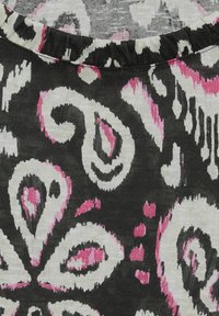 Tela negra con un audaz patrón floral en blanco y rosa, con diseños y detalles en espiral, texturizada con un acabado ligero y tejido.