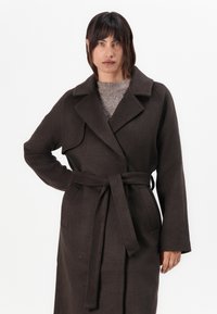 Brown wool blend coat with a belted waist, notch collar, and side pockets. Features a relaxed fit and long sleeves. Soft texture.