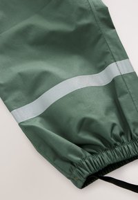 Pantaloni leggeri verdi con una striscia riflettente argento, vita elastica e texture liscia per comfort e utilità.
