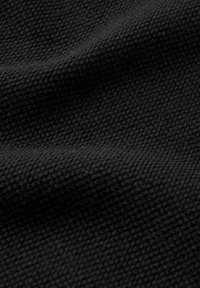 Svart vävt tyg med en strukturerad mönster, som visar subtil djup och skugga. Materialet ser mjukt och flexibelt ut.