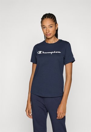 T-shirt en coton bleu marine avec un logo "Champion" blanc sur le devant. Design classique à col rond avec des manches courtes et une coupe décontractée.
