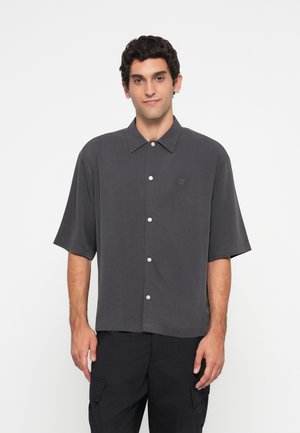 Gray short-sleeve shirt with a button-down collar, featuring a subtle embroidered emblem and contrasting button closures. Smooth fabric texture.