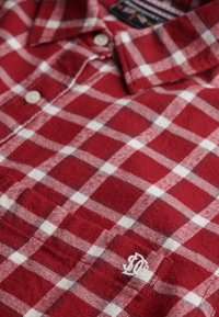Camicia in flanella a quadri rossi e bianchi con colletto button-down, logo ricamato sulla tasca e tessuto morbido e strutturato.