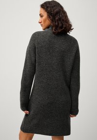 Donkergrijze gebreide jurk met een hoge kraag, lange mouwen en een relaxte fit, met ribbeldetails bij de mouwen en de zoom.