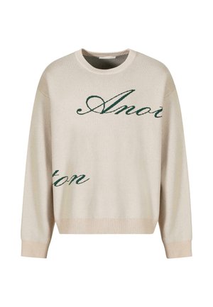 Jersey de punto beige con texto verde en cursiva. Cuello y puños acanalados, corte relajado, con una textura suave.