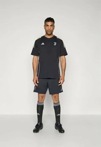 Čierny dres s bielymi a neónovými akcentmi, doplnený čiernymi šortkami a čiernymi ponožkami dĺžky po kolená. Obsahuje logo Adidas a emblem Juventusu.