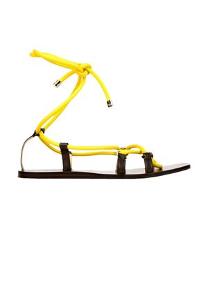 Flad sandal med tynd sort sål, sorte remme og lysegule reb-snørebånd bundet omkring anklen.