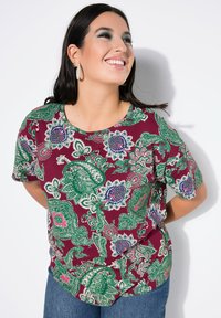 Kurzärmliges, kastanienbraunes T-Shirt mit einem floralem Paisleymuster in Grün, Pink und Blau. Weicher Stoff, runder Ausschnitt, lockere Passform.