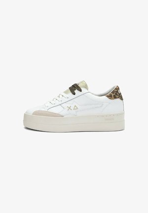 Sneaker platform bianca con toppa beige sulla punta, lacci neri, linguetta sul tallone con stampa leopardata e simboli ricamati in oro sul lato.
