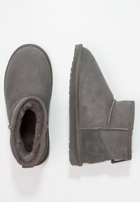 Graue Wildleder-Stiefeletten mit einer weichen Innenauskleidung, abgerundetem Zehenbereich und texturiertem Gummisohle. Verfügt über eine genähte Naht an der Seite.
