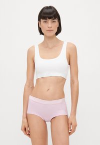 Λευκό σουτιέν χωρίς ραφές και ανοιχτό ροζ μπόξερ με μαλακή υφή. Το σουτιέν διαθέτει τετράγωνη γραμμή στο ντεκολτέ και λογότυπο στη ζώνη, ενώ τα μπόξερ έχουν ετικέτα στη ζώνη.