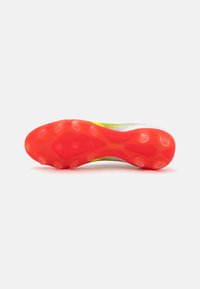 Soccer cleat outsole in vibrant red with circular studs. Upper features a mix of white mesh and yellow accents, showcasing a lightweight design.