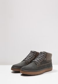 Zapatos de caña alta de ante gris con suelas de goma marrón. Presentan un diseño con cordones, acentos de costura y un cuello acolchado.
