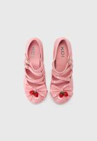 Roze lakleren schoenen met drie bandjes, strikdetail en aardbeienaccenten op de neus. Textuur en glanzende afwerking.
