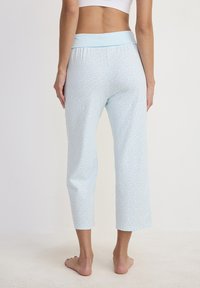 Pantaloni capri azzurri chiari realizzati in tessuto morbido, con una ampia vita elastica e piccoli motivi a pois. 