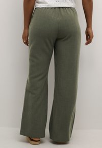 Green wide-leg pants made of lightweight fabric, featuring a soft, textured surface and an elastic waistband. Natural fibers are visible.