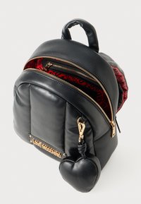 Črn nahrbtnik Love Moschino z zlatimi zadrgami, rdečo vzorčeno notranjostjo in ključkom v obliki srca, pritrjenim na sprednji žep.