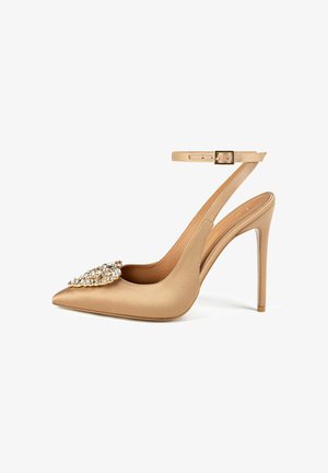 Nude satin high-heeled pump with a pointed toe, adjustable ankle strap, and a rhinestone-embellished detail on the vamp.