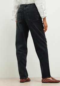 Jeans in denim nero a vita alta, gamba dritta, design a cinque tasche, con due tasche posteriori e dettagli di cucitura minimali.