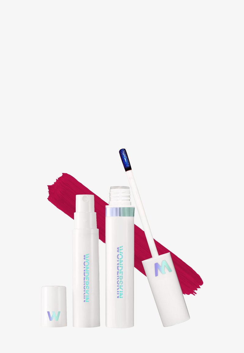 Drie cosmetische verpakkingen van Wonderskin: een sprayfles, een tube met applicator, en een dop, allemaal in het wit met holografische accenten.