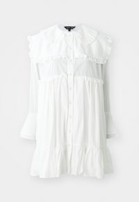 Robe blanche à manches longues avec bouts de manches boutonnés, grand col à volants, et détails à volants en étages le long de la poitrine, de la taille et de l'ourlet.