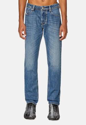 Lysblå straight-leg jeans med bløde vaskede detaljer, fem-lomme design, metalknaplukning og kontrasterende syninger. Bæres med sorte sneakers.