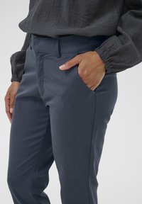 Gray tailored pants with a smooth texture, slim fit, and side pockets. The waistband is neatly finished, enhancing structured design.