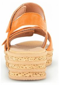 Orange lædersandal med en tekstureret, lagdelt kilehæl. Åben hældesign med justerbare stropper for optimal pasform og komfort.