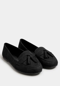 Svarta mocka tofflor med rund tå, prydda med en dekorativ tofs framtill och subtila sömnadsdetaljer på ovandelen.