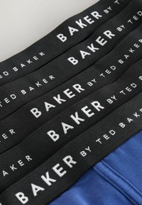 Quatre ceintures élastiques noires avec la marque blanche "BAKER by Ted Baker" sur tissu noir, au-dessus d'un vêtement bleu.