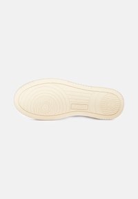 Suola di sneaker in gomma beige, con un motivo testurizzato che presenta scanalature circolari e lineari e il nome del marchio "AUTRY" impresso.