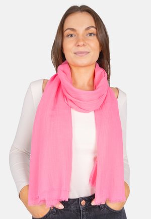 Light pink scarf made of soft, sheer fabric. Features fringed edges and is styled draped around the neck.