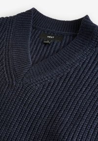 Marineblauw gebreid trui met een ribbeltextuur en een V-hals ontwerp. Label 'NEXT' zichtbaar op de hals.