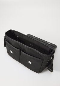 Borsa a tracolla nera in tessuto con finitura testurizzata, dotata di due tasche esterne e chiusura superiore con zip. Accenti in metallo argentato visibili.