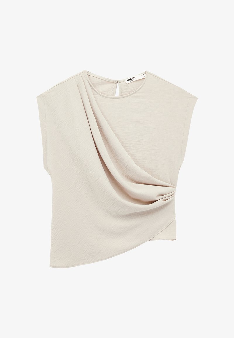 Beżowa bluzka z krótkim rękawem z asymetrycznie ułożoną tkaniną i okrągłym dekoltem z małym klapowym zapięciem na guziczek z tyłu.