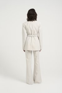 Lys beige skreddersydd dress med en innsvingt elastisk midje på jakken, med lange ermer og vide bukser. Glatt tekstur, minimalistisk design.