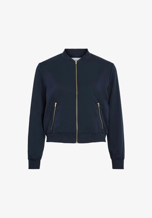 Giacca bomber di colore blu navy realizzata in tessuto liscio, con chiusura frontale zip, due tasche laterali con zip e polsini e orlo a costine. Dettagli con zip dorate.