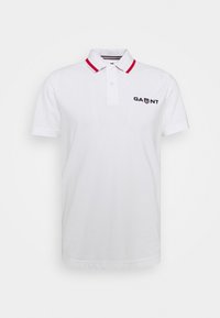 Biała koszulka polo z czerwonymi paskami na kołnierzyku, krótkie rękawy oraz haftowane logo "GAUNT" w czerni po lewej stronie. Klasyczny krój i materiał bawełniany.