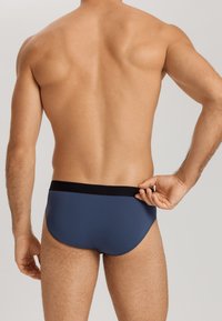 Mutande da uomo in tessuto blu navy con una texture liscia, dotate di una cintura elastica nera con dettagli del logo.