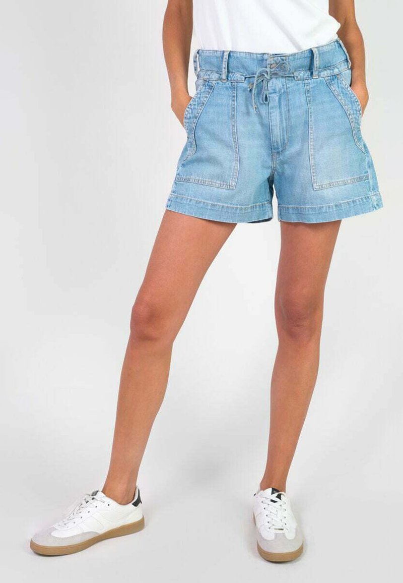 Shorts en denim bleu clair avec une taille à cordon, poches avant et ourlet replié. Associés à des baskets blanches avec des accents gris.