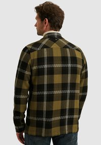 Groen en zwart geruit shirt, met een houndstooth patroon, lange mouwen, een puntige kraag en contrasterende witte stikdetails.