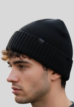 Black knitted beanie with a ribbed design and a folded brim. Features a small branded tag on the side. Soft texture suitable for cold weather.