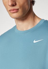 Light blue cotton t-shirt with a crew neckline and a white Nike logo on the left chest; smooth texture and minimal design.