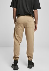 Karakke sweatpants med elastisk midje og mansjetter, med en baklomme. Båret med svarte ankelboots. Glatt bomullsblandingsstoff.