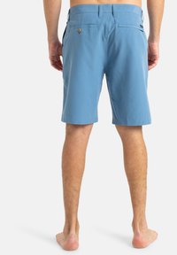 Pantalones cortos azules para hombre, fabricados en un tejido ligero, con una textura suave, ajuste estándar y bolsillos traseros con cierres de botones.